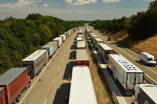 pexels-photo-13008065-13008065 A high-angle shot of trucks and trailers in traffic on a highway in England beneath a bright sky.